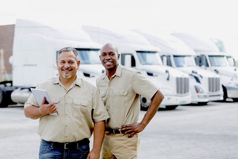A fleet manager and a driver stand in front of their fleet.