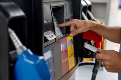 A truck driver pays for gas at the pump with a fleet card.
