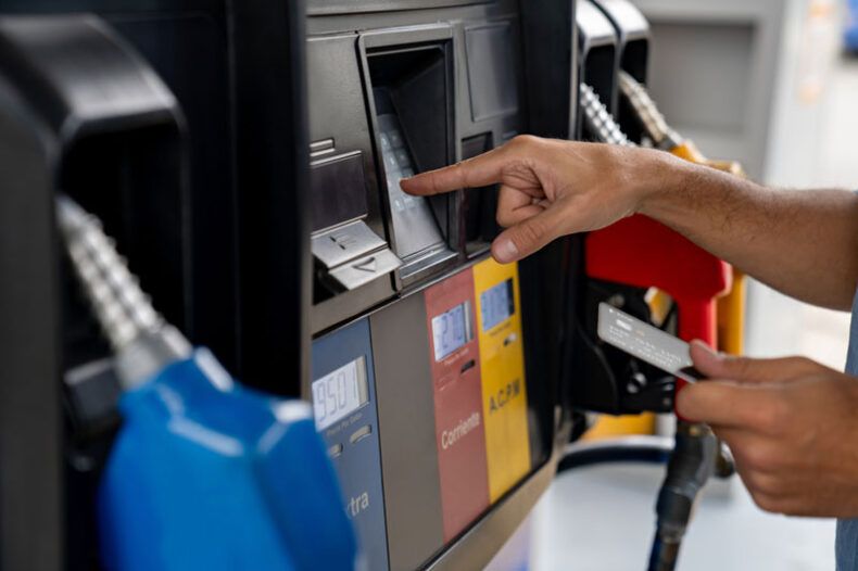 A truck driver pays for gas at the pump with a fleet card.