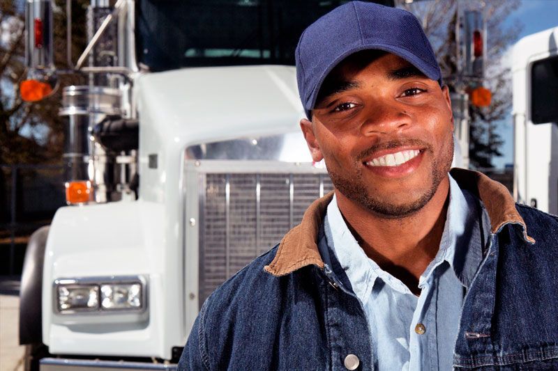 A happy truck driver stands outside his fleet vehicle.