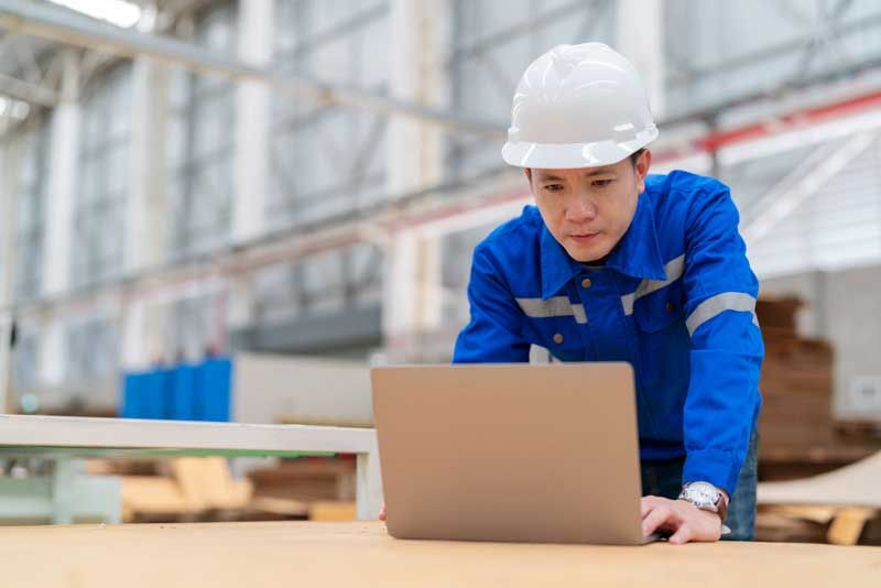 A business owner sees how fleet cards make his business more efficient while viewing data on his computer screen wearing a hardhat.
