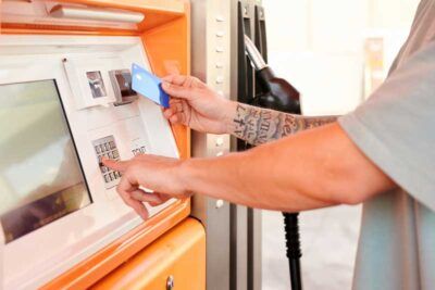 A truck driver pays for fuel with a fleet fuel card at a kiosk at a gas station.